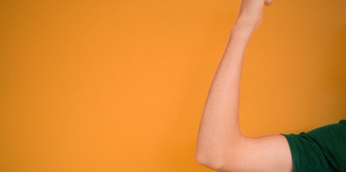 Angespannter Oberarm vor orangenem Hintergrund