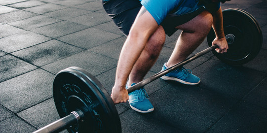 Person mit Langhantelstange beim Kreuzheben